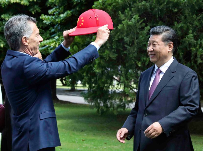 El mandatario chino Xi Jinping recibe un casco de polo decorado con la bandera de China de parte del presidente argentino Mauricio Macri. (AP)