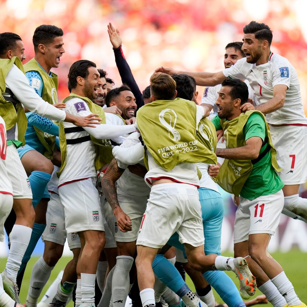 Jugadores de Irán celebran con euforia luego de que Rouzbeh Cheshmi (oculto) anotara el primer gol en los minutos añadidos después que los primeros 90 minutos se agotaron con un empate 0-0 con Gales.