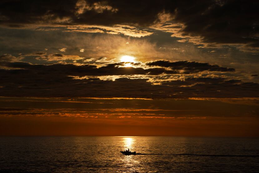 A primera hora de la mañana, un pescador deportivo navega sobre el mar en calma de camino a los bancos de pesca de lubina rayada frente a la costa de Kennebunkport, Maine.