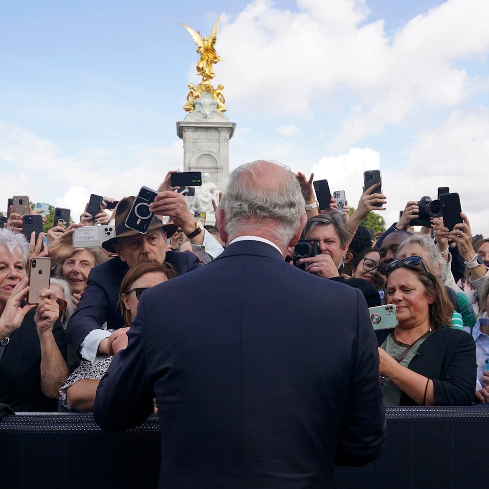 Britain's King Charles III, back to camera, greets well-wishers as he walks by the gates of Buckingham Palace following Thursday's death of Queen Elizabeth II, in London, Friday, Sept. 9, 2022. King Charles III, who spent much of his 73 years preparing for the role, planned to meet with the prime minister and address a nation grieving the only British monarch most of the world had known. He takes the throne in an era of uncertainty for both his country and the monarchy itself. (Yui Mok/Pool Photo via AP)