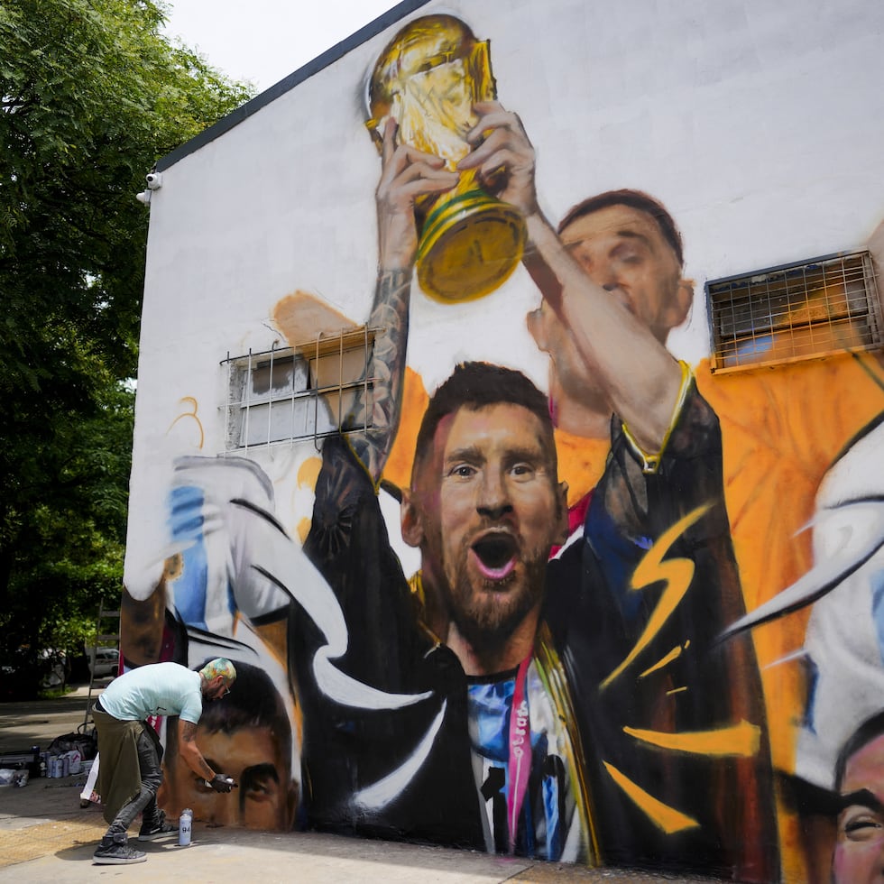 El artista Maxi Bagnasco pinta su mural con la imagen del astro Lionel Messi alzando la Copa de Mundo en Buenos Aires, Argentina, el jueves 22 de diciembre de 2022.
