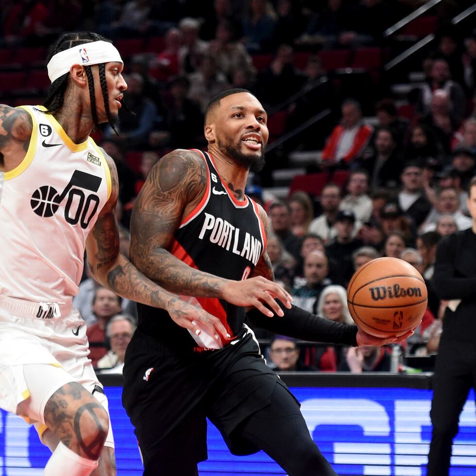 Damian Lillard (derecha), de los Trail Blazers de Portland, ataca hacia el canasto ante la presión de su rival del Jazz de Utah, Jordan Clarkson.