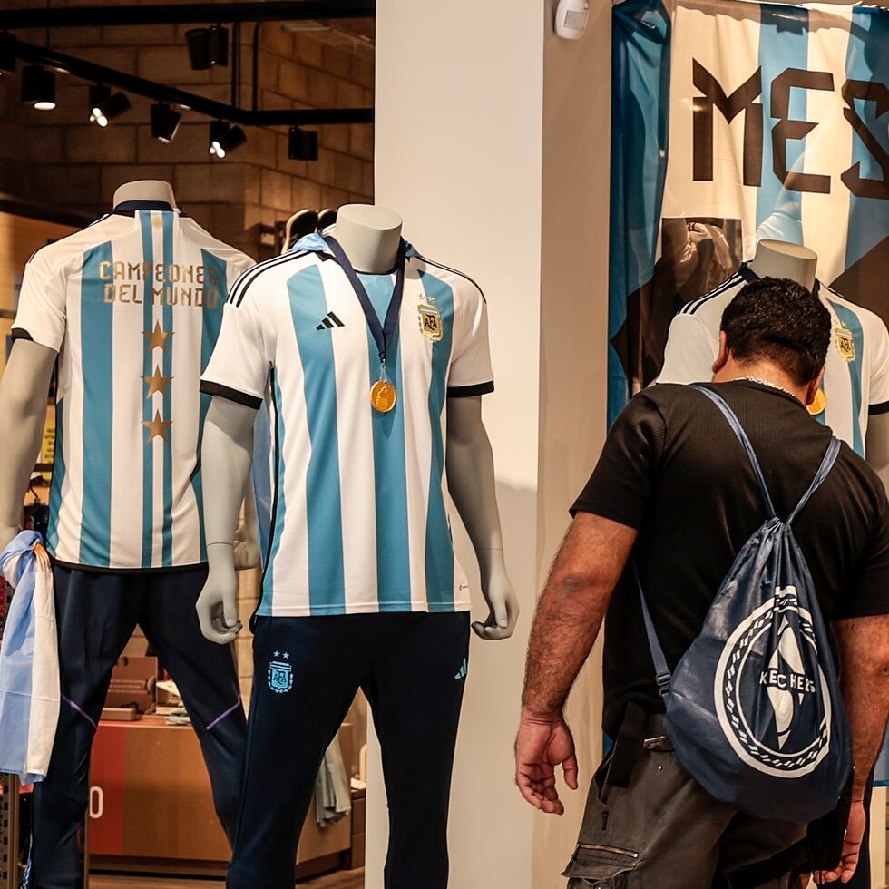 Aficionados de la selección argentina de fútbol acuden a una tienda a comprar la nueva camiseta de la selección con las tres estrellas y el escudo de campeones del mundo.