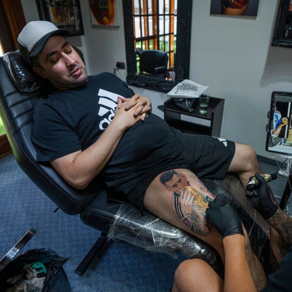 El artista César "Yeyo" Molina tatúa en la pierna de Sebastián Fernández una gran imagen del futbolista Lionel Messi con la Copa del Mundo en Buenos Aires, Argentina, el jueves 29 de diciembre de 2022. “La locura por el mundial es impresionante”, contó.