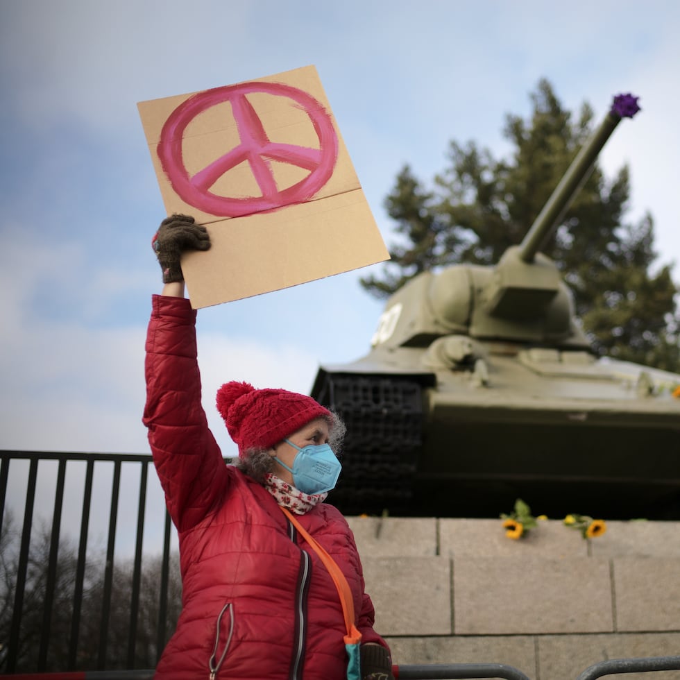 A woman shows a peace sign in front of a Russian WWII tank at the Soviet War Memorial at the bolevard 'Strasse des 17. Juni' alongside a rally against Russia's invasion of Ukraine in Berlin, Germany, Sunday, Feb. 27, 2022. (AP Photo/Markus Schreiber)