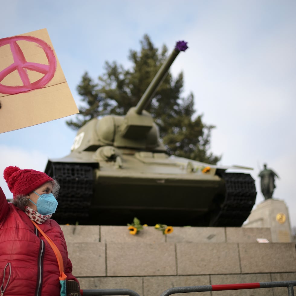 A woman shows a peace sign in front of a Russian WWII tank at the Soviet War Memorial at the bolevard 'Strasse des 17. Juni' alongside a rally against Russia's invasion of Ukraine in Berlin, Germany, Sunday, Feb. 27, 2022. (AP Photo/Markus Schreiber)