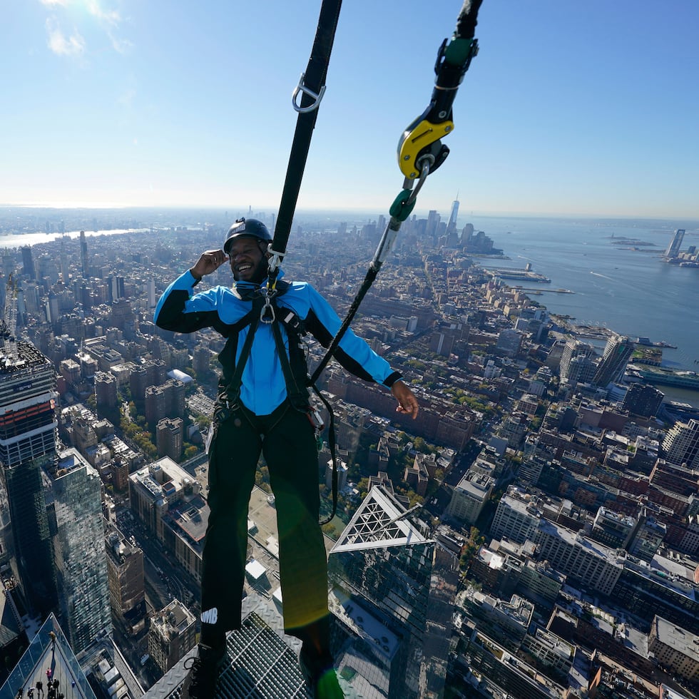 El guía Jason Johnson se inclina hacia afuera desde el borde de una plataforma en la cima del edificio.