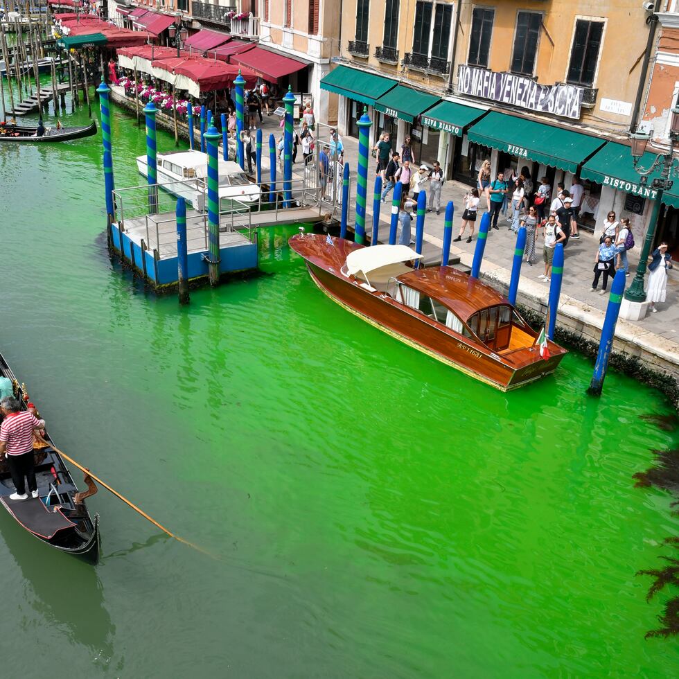 Una góndola navega por el histórico Gran Canal de Venecia, manchado por un líquido verde, el domingo 28 de mayo de 2023. La policía investiga la fuente de dicho líquido. (Foto AP/Luigi Costantini)