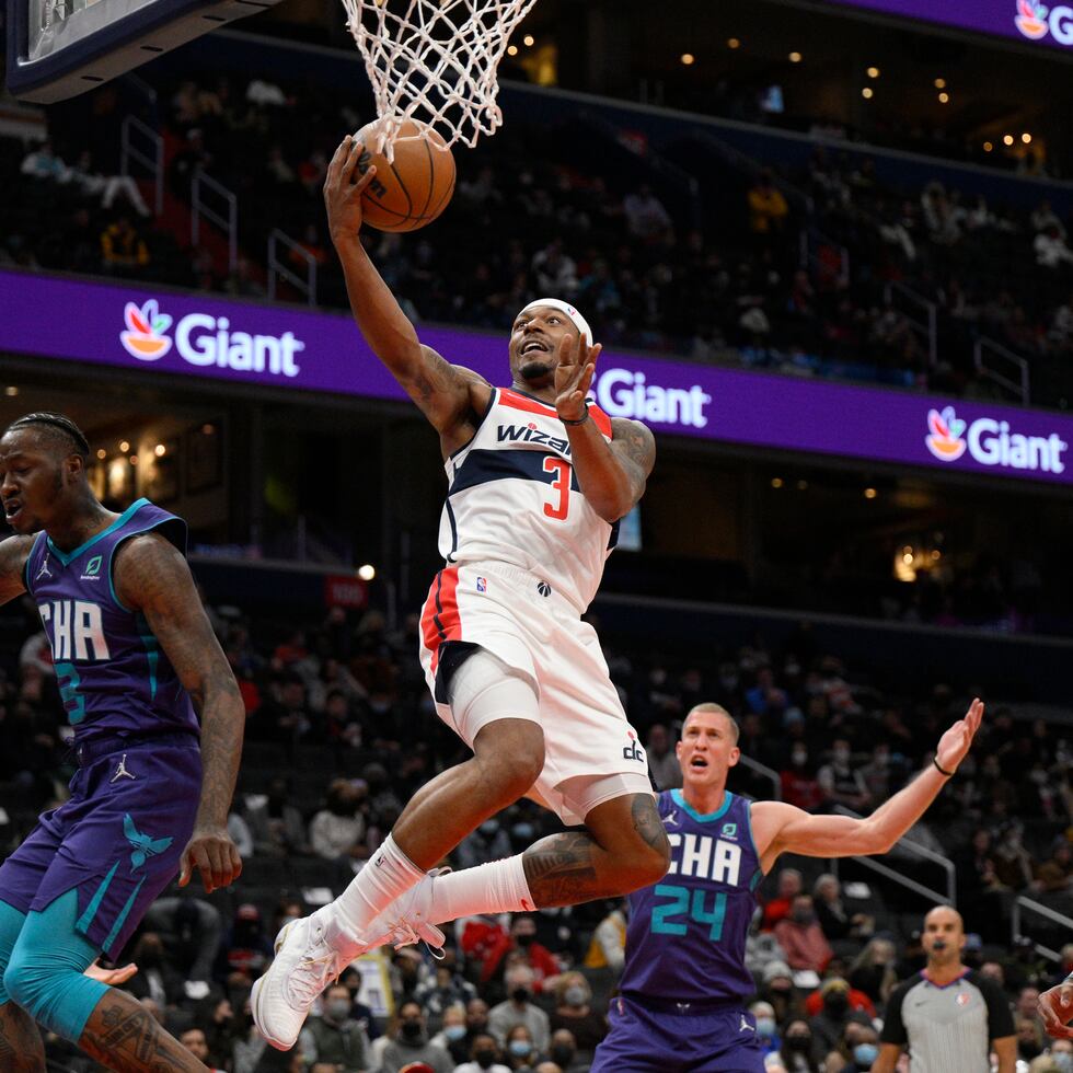 El base de los Wizards de Washington, Bradley Beal, avanza hacia la canasta mientras lo defienden ,Terry Rozier (izquierda) y Mason Plumlee, de los Hornets de Charlotte.