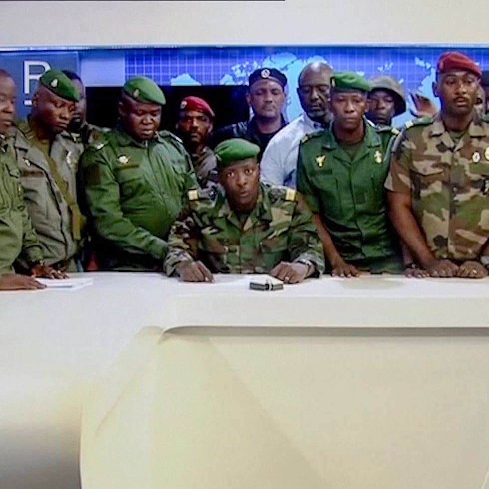 En esta imagen tomada de un video, un militar que se identificó a sí mismo como portavoz del Comité Nacional para el Progreso y Desarrollo, rodeado de otros militares, se dirige a la nación desde las instalaciones de la televisora estatal, el domingo 5 de septiembre de 2021, en Conakri, Guinea. (Radio Television Guineenne via AP)