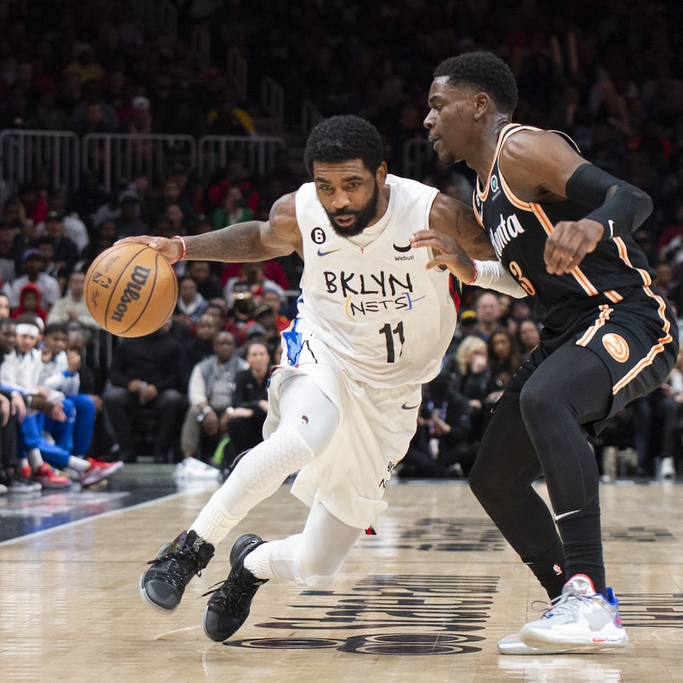 Kyrie Irving (11), de los Nets de Brooklyn, conduce el balón ante la marca defensiva de Aaron Holiday, de los Hawks de Atlanta, durante la segunda mitad del juego de baloncesto de la NBA.