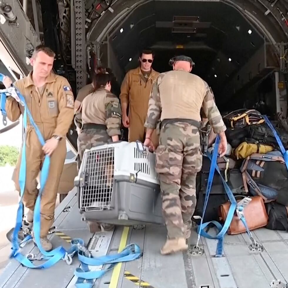 En esta imagen de video proporcionada por las fuerzas armadas francesas, personal militar carga en un avión las pertenencias de personas evacuadas, el domingo 23 de abril de 2023, en el aeropuerto de Jartum, Sudán.