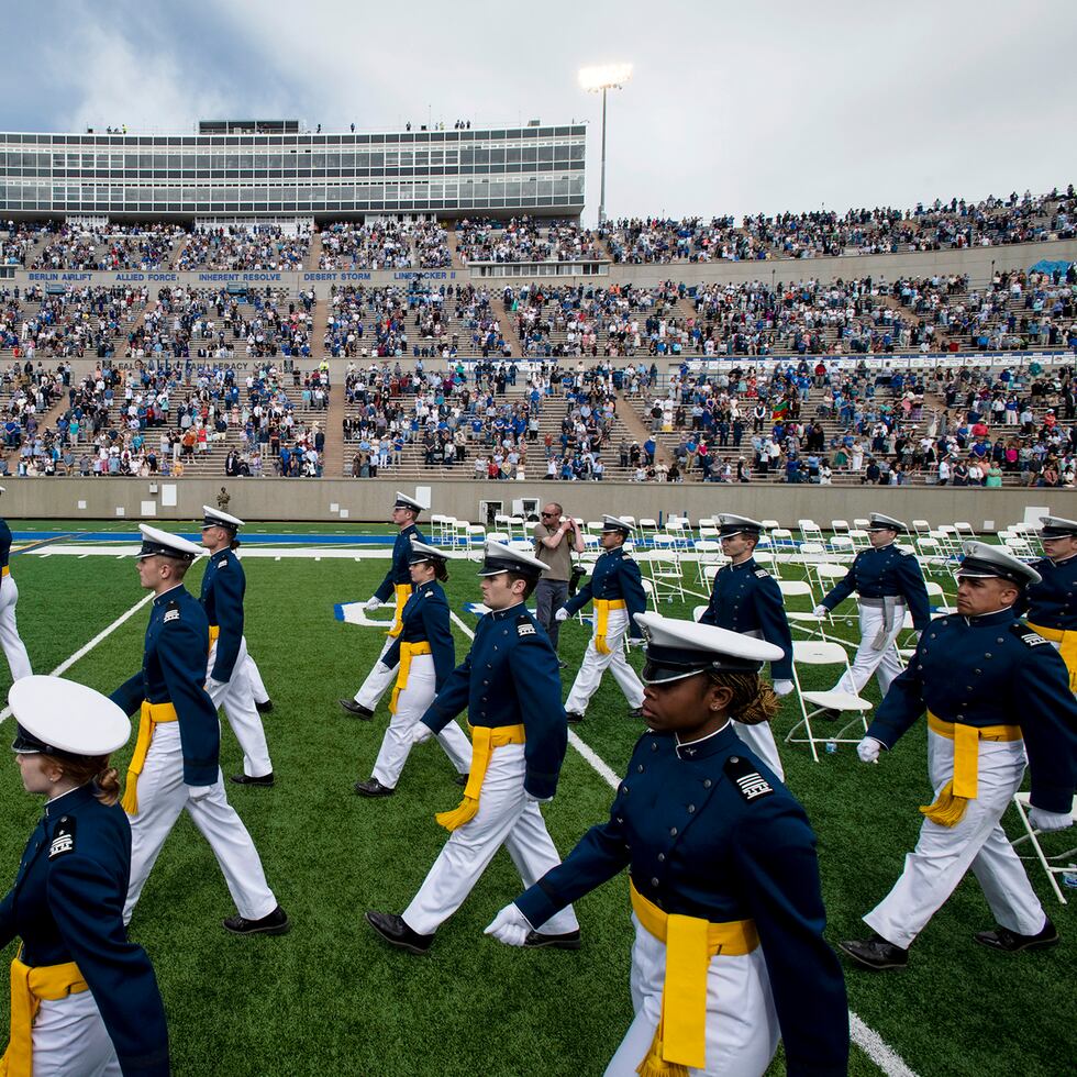 Cadetes de la Academia de la Fuerza Aérea caminan hacia sus asientos ante los aplausos de amigos y familiares durante la ceremonia de graduación de la generación 2021 de la Academia de la Fuerza Aérea, el 26 de mayo de 2021, en Colorado Springs, Colorado. (Chancey Bush/The Gazette via AP, Archivo)