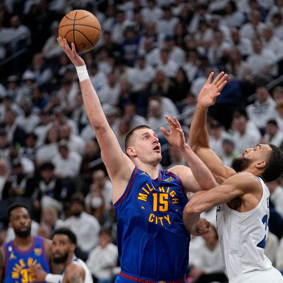 El pivot de los Nuggets de Denver, Nikola Jokic, tira al canasto con un gancho sobre Rudy Gobert, de los Timberwolves de Minnesota.