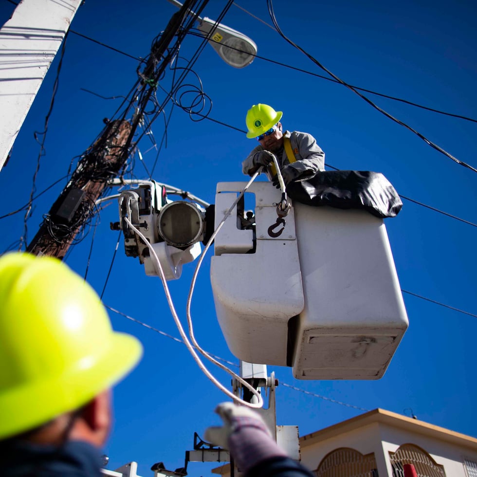 Empleados de la AEE cambian el tendido eléctrico en un poste.