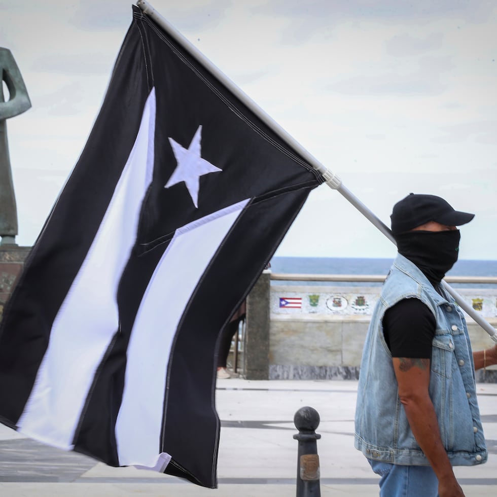 Un manifestante carga la bandera de "luto" de Puerto Rico.