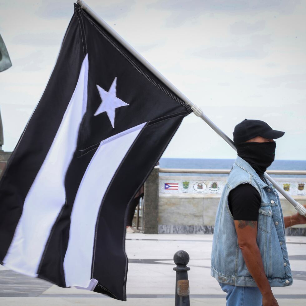 Un manifestante carga la bandera de "luto" de Puerto Rico.