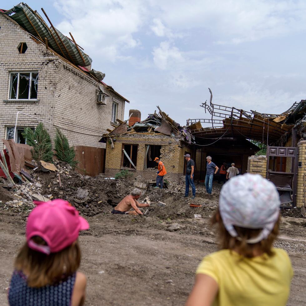 Niños observan a trabajadores que remueven los escombros tras un ataque con cohete a una vivienda en Kramatorsk, región de Donetsk, este de Ucrania, 12 de agosto de 2022. No se informó de heridos en el hecho. (AP Foto/David Goldman)