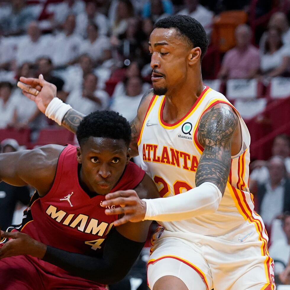 El base del Heat de Miami Victor Oladipo avanza hacia la canasta mientras lo defiende el alero de los Hawks de Atlanta John Collins.