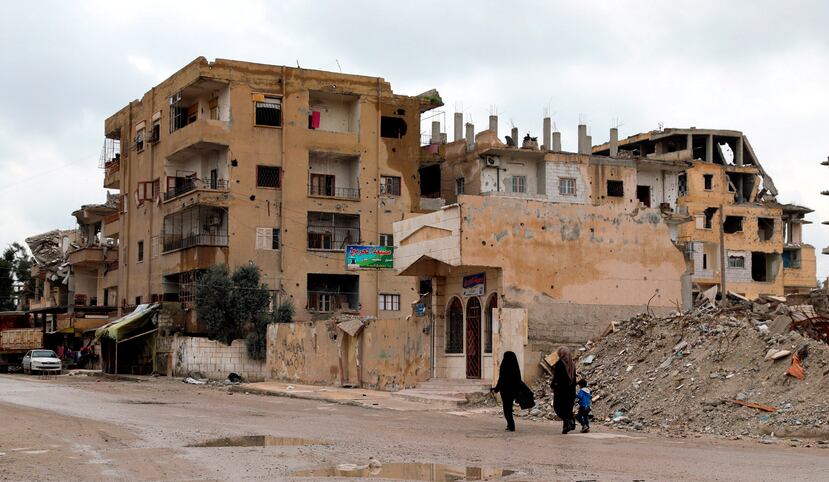 Dos mujeres sirias caminan junto a un niño frente a casas derruidas en Al Raqa (Siria), ciudad que fue la capital de facto de los yihadistas del grupo Estado Islámico.