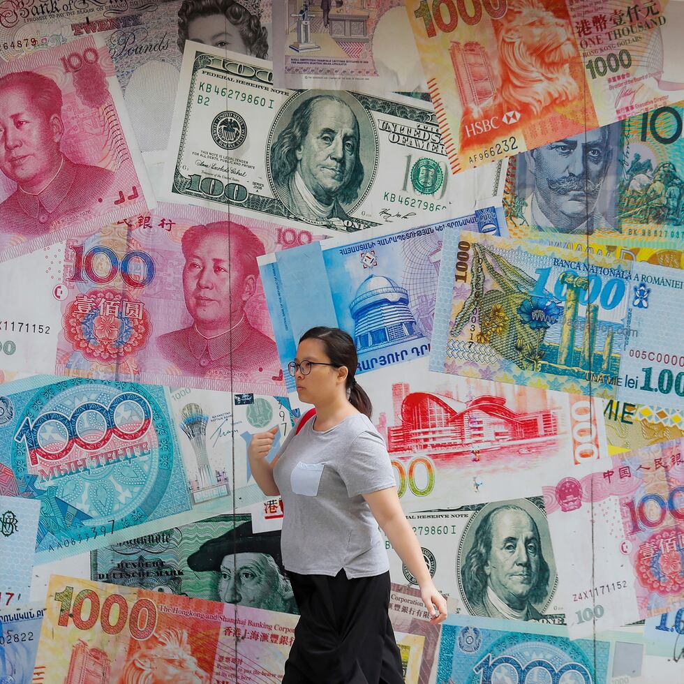 Fotografía de archivo del 6 de agosto de 2019 de una mujer caminando frente a una casa de cambio en Central, en distrito comercial de Hong Kong. (AP Foto/Kin Cheung, Archivo)