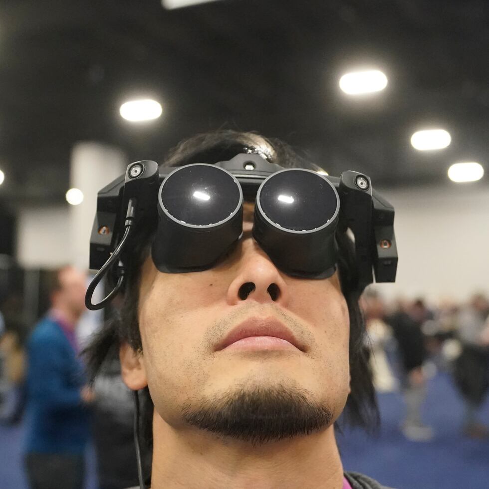 Takuma Iwasa usa el Megane X en el stand de Shiftall previo a la apertura de la feria tecnológica CES, el martes 3 de enero de 2023 en Las Vegas. Megane X es un dispositivo de realidad virtual ultraligero y ultracompacto.