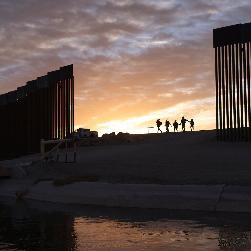 Un par de familias migrantes de Brasil atraviesan un hueco en el muro fronterizo para llegar a Estados Unidos después de cruzar desde México en Yuma, Arizona.