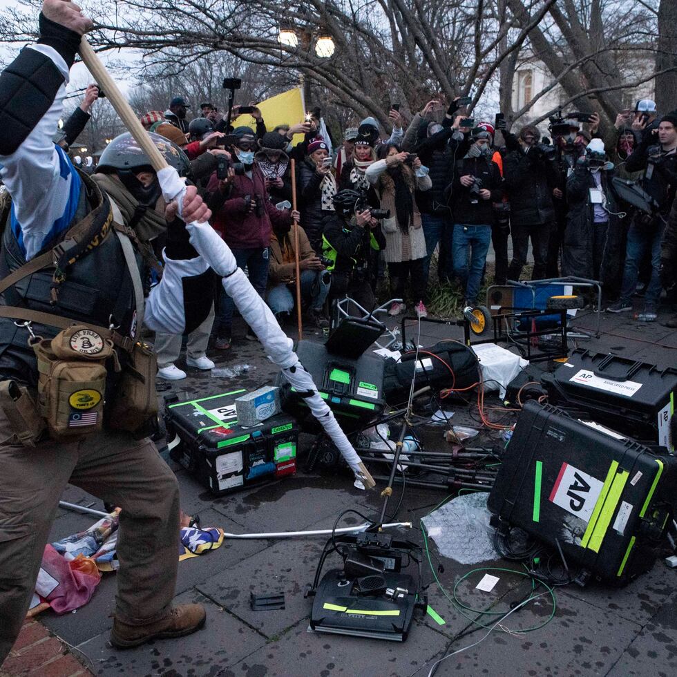 Demonstrators break TV equipment outside the the U.S. Capitol on Wednesday, Jan. 6, 2021, in Washington.  (AP Photo/Jose Luis Magana)