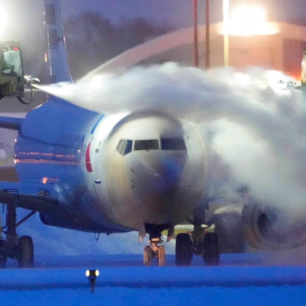 An American Airlines plane is de-iced as high winds whip around 7.5 inches of new snow at Minneapolis-St. Paul International Airport Thursday, Dec. 22, 2022. Temperatures plunged far and fast Thursday as a winter storm formed ahead of Christmas weekend, promising heavy snow, ice, flooding and powerful winds across a broad swath of the country and complicating holiday travel. (David Joles/Star Tribune via AP)