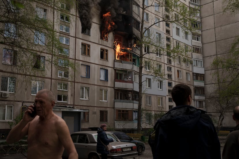 Personas miran un incendio en un edificio luego de un bombardeo del ejército ruso en Kharkiv, Ucrania.