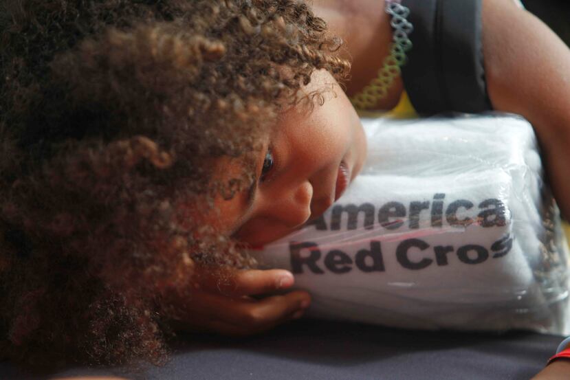 Una niña recuesta su cabeza sobre unas toallas proporcionadas por la Cruz Roja estadounidense. (AP Foto/Ricardo Arduengo)