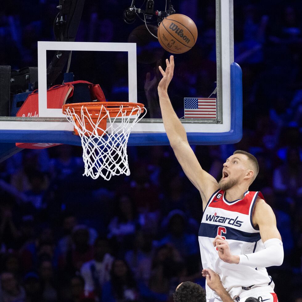 Kristaps Porzingis, pívot de los Wizards de Washington, dispara frente a Georges Niang  y Danuel House Jr., de los 76ers de Filadelfia.