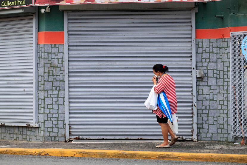 Una mujer camina con mascarillas por la comunidad Barrio Obrero.