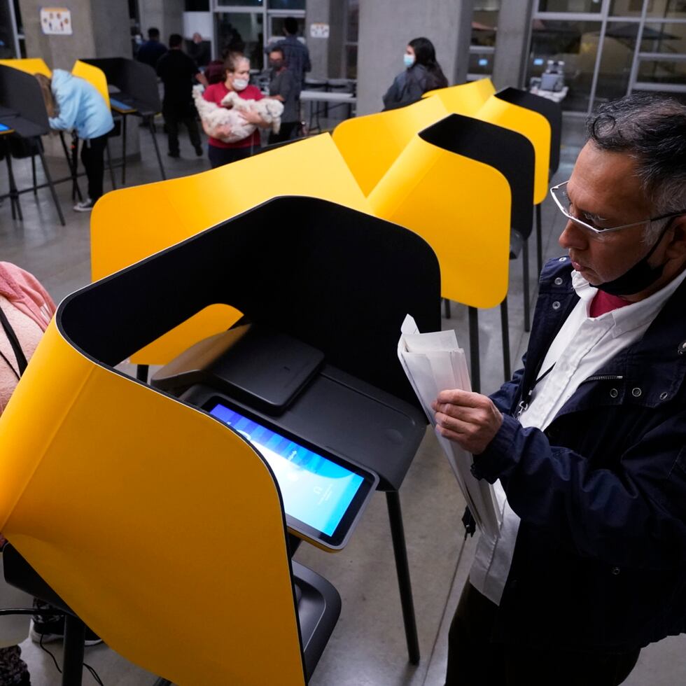 Fernando Dejo, right, and Sabina Vasquez retrieve paper ballots from ballot marking devices, or vote recorders, as a polling place closes in Los Angeles on Tuesday, Nov. 3, 2020. (AP Photo/Damian Dovarganes)