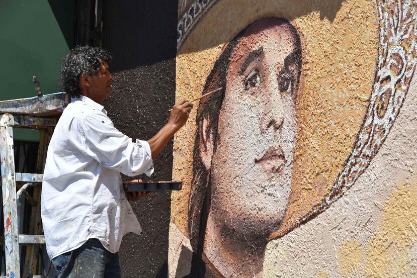 El pintor salvadoreño Héctor Ponce agrega los últimos detalles al mural dedicado al fallecido cantautor mexicano Juan Gabriel (EFE / Iván Mejía)
