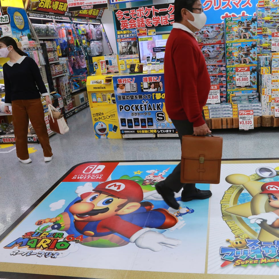 Un comprador pasa por encima de un anuncio de Super Mario, de Nintendo, en una tienda de electrónica en Tokio.
