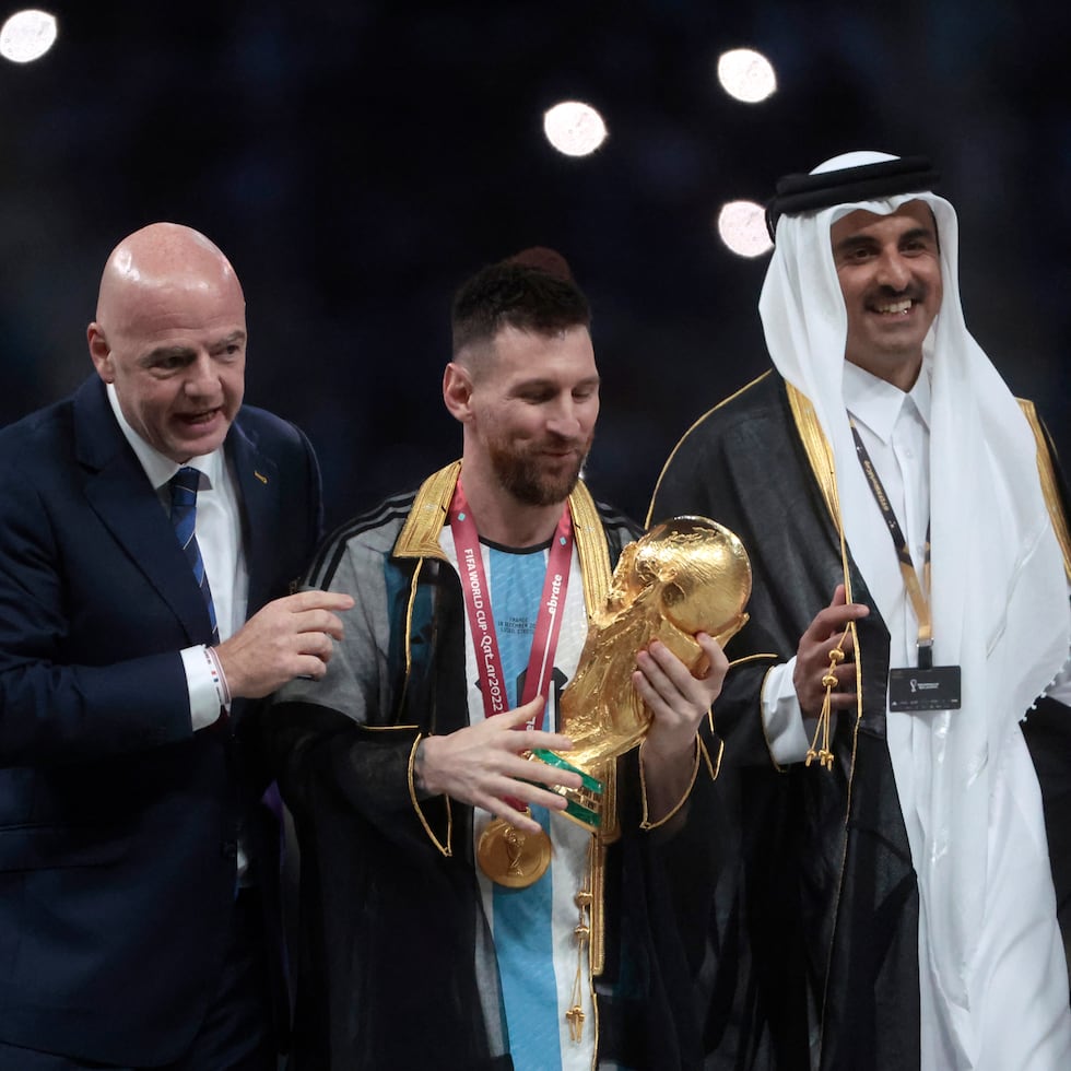 Lionel Messi (centro) posa con el trofeo de la Copa del Mundo junto a el presidente de la FIFA Giovanni Vincenzo (izquierda) y el Emir del Estado de Catar, Tamim bin Hamad Al Thani.