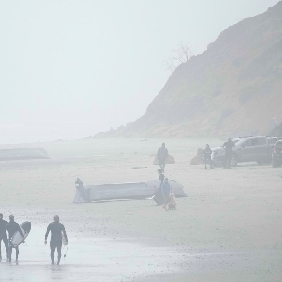 Dos botes, uno de ellos volteado, en Blacks Beach este domingo en San Diego.