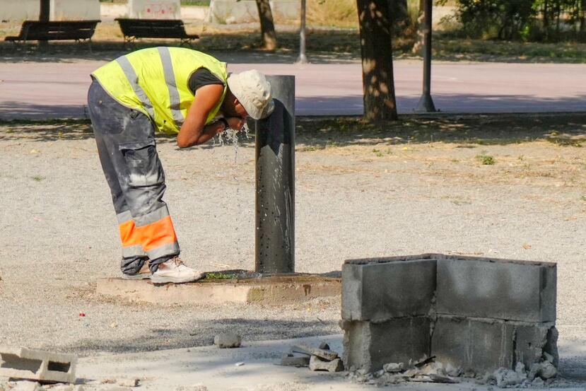 Un trabajador se refresca en una fuente de un parque de Lleida, este viernes en que todas las comarcas de Cataluña entran en el máximo nivel de alerta por la ola de calor.