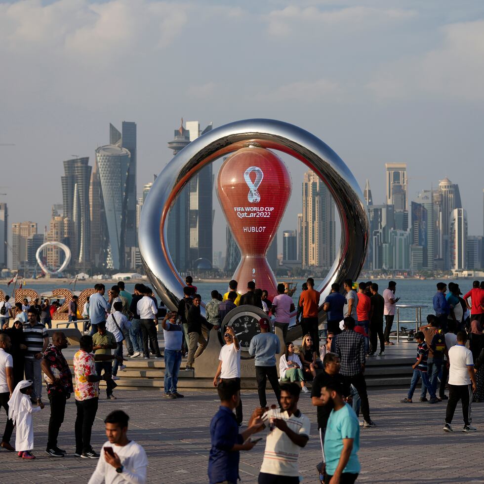 ARCHIVO - Un grupo de personas se reúne en torno de un reloj que marca la cuenta regresiva para la inauguración del Mundial en Doha, Qatar, el 11 de noviembre de 2022 (AP Foto/Hassan Ammar, archivo)