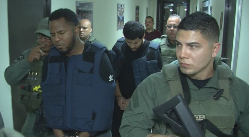 Waldemar Febres Sánchez (con el chaleco antibalas) y Edison Merced Olivera (detrás de Febres Sánchez) son llevados a las oficinas del Cuerpo de Investigaciones Criminales (CIC) en el cuartel general en Hato Rey. (Suministrada)