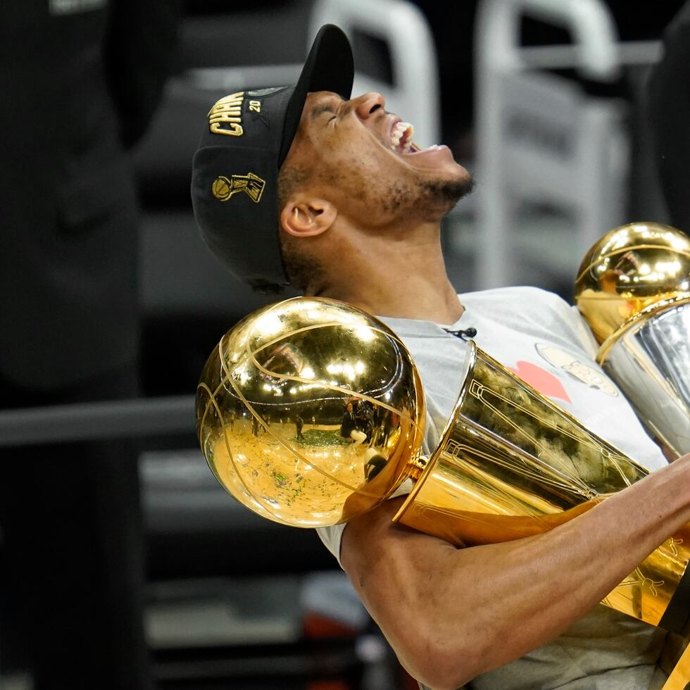 Antetokounmpo grita de alegría con los trofeos de campeonato de la NBA y Jugador Más Valioso de las Finales.