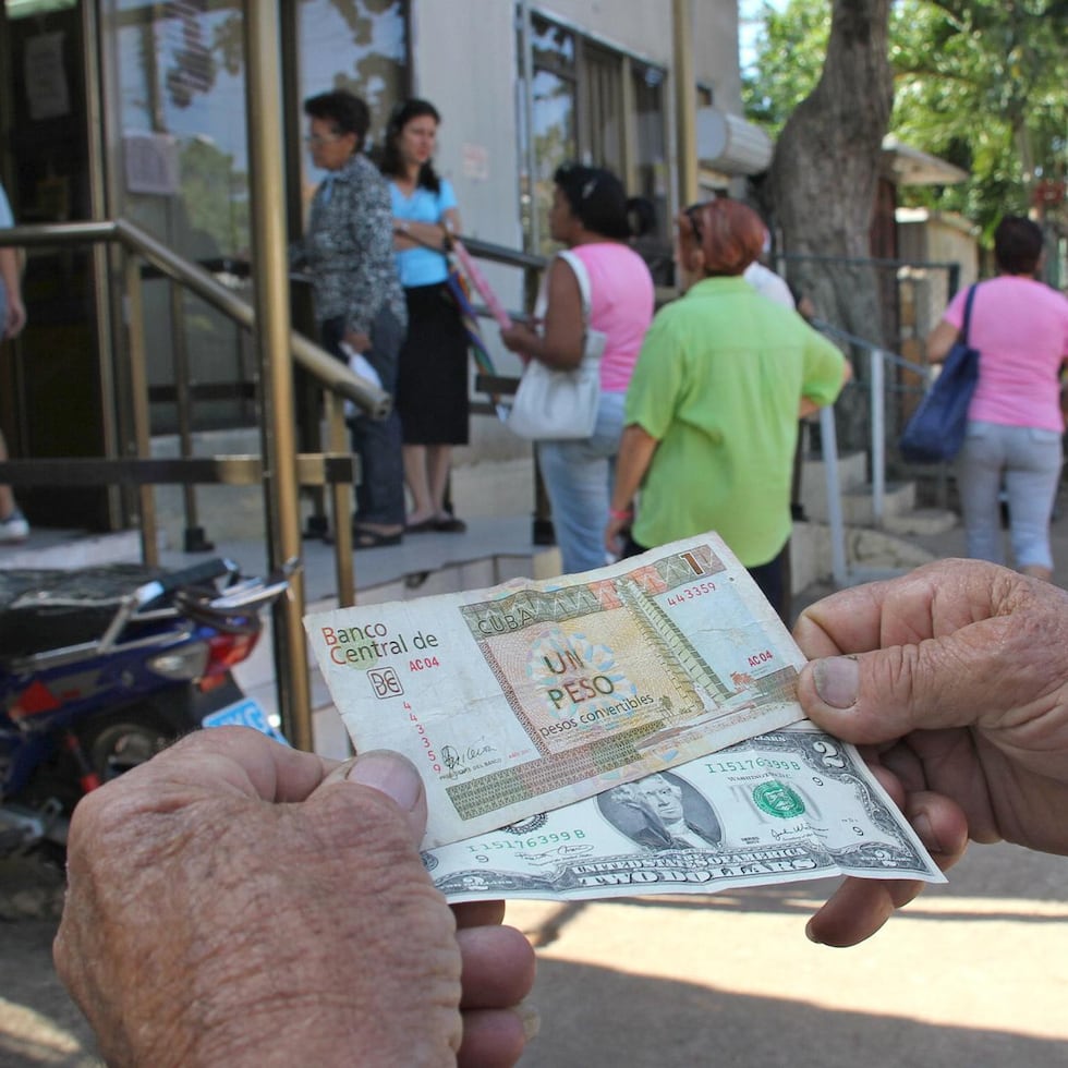 Un hombre muestra un peso convertible cubano y un dólar estadounidense frente a una oficina de la Western Union en La Habana (Cuba), en una fotografía de archivo. EFE/Rolando Pujol
