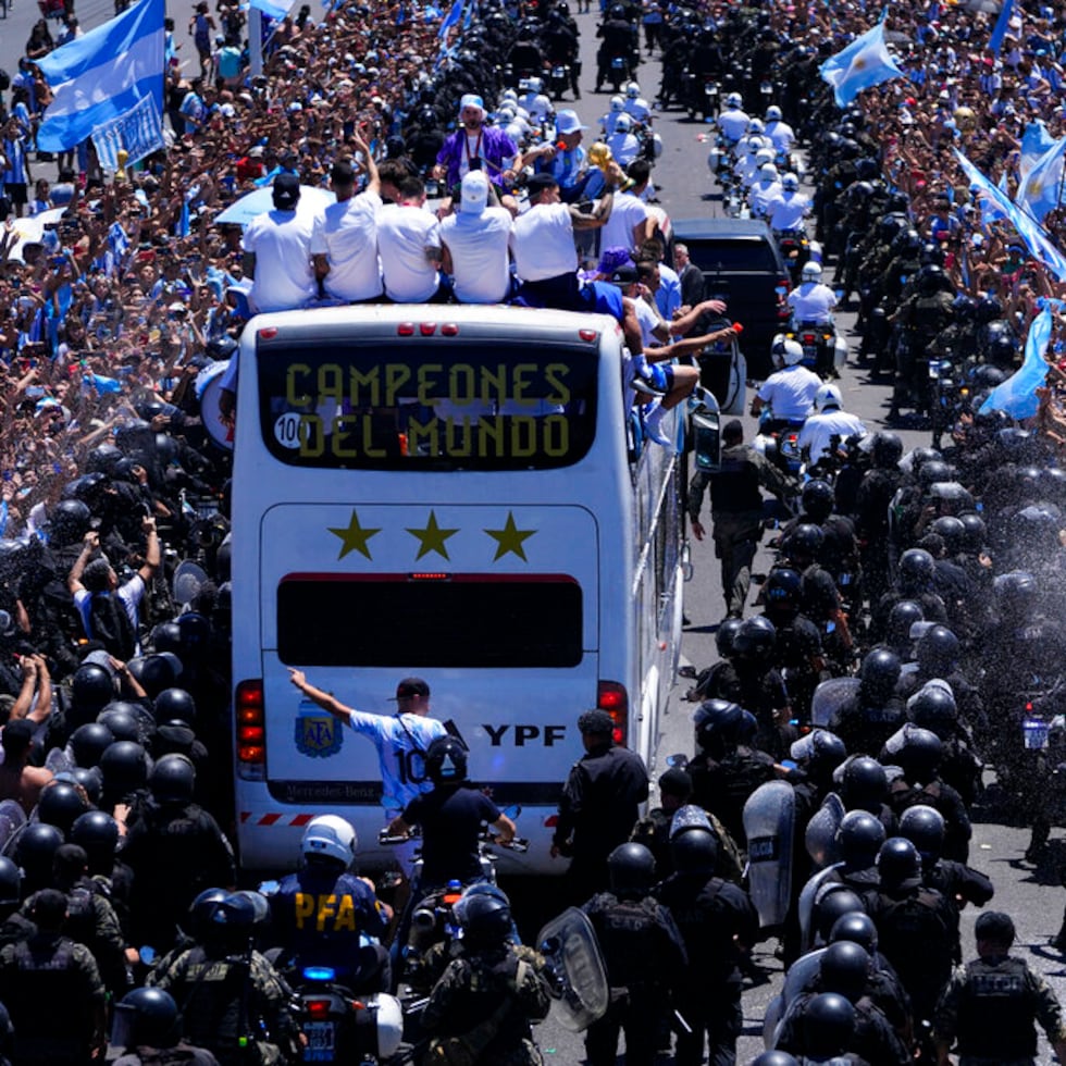 The Argentine soccer team shows off their World Cup trophy from a bus as they are welcomed home in Buenos Aires, Argentina, Tuesday, Dec. 20, 2022. The bus window reads in Spanish "World Champions." (AP Photo/Natacha Pisarenko)