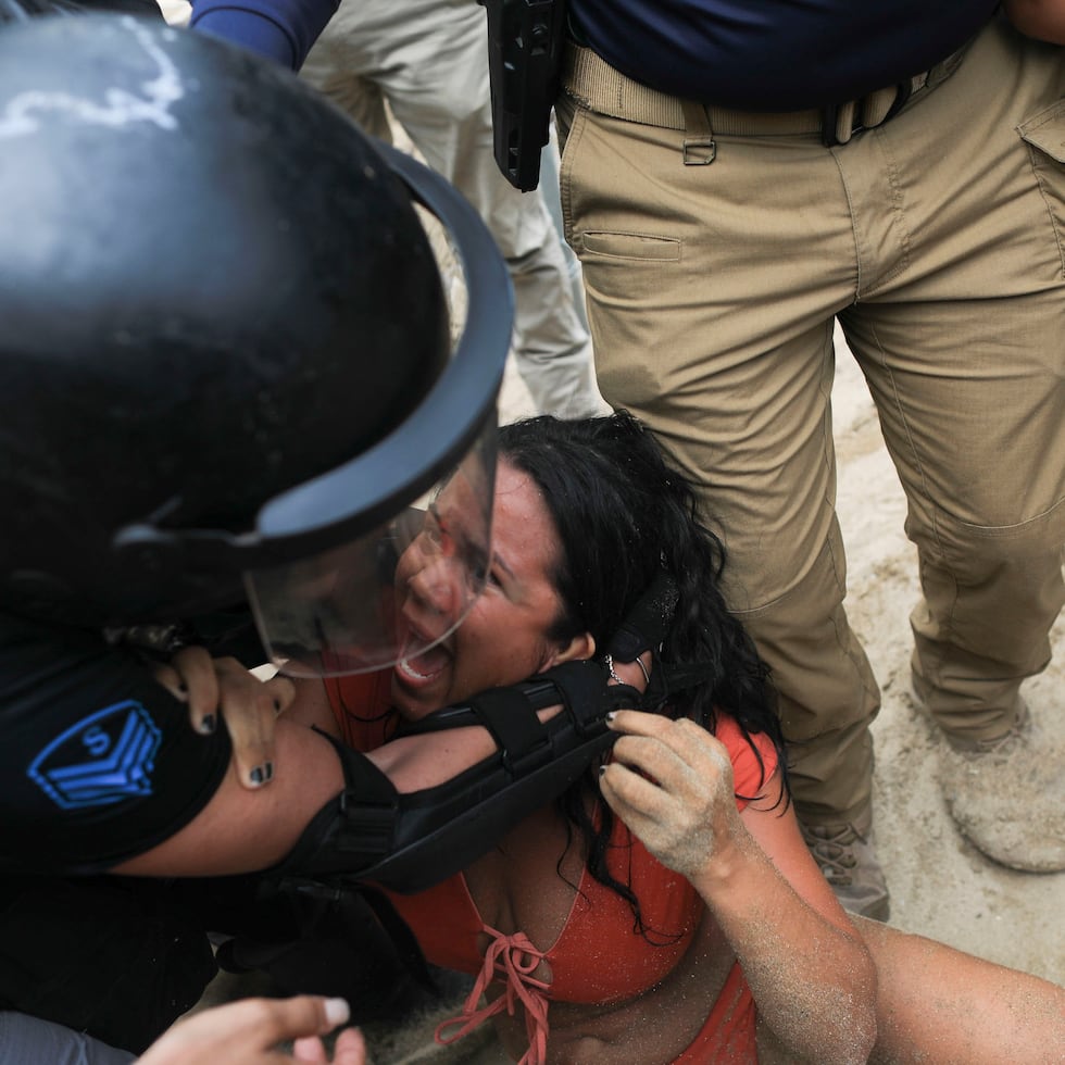 Momento cuando agentes de la Policía sacan a la fuerza a una manifestante.