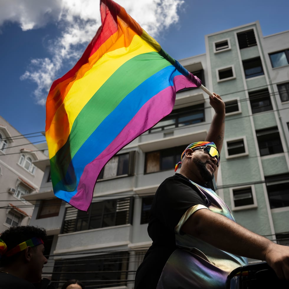 Uno de los participantes de la Parada Orgullo Gay en San Juan, sostiene la bandera multicolor que identifica a la comunidad.