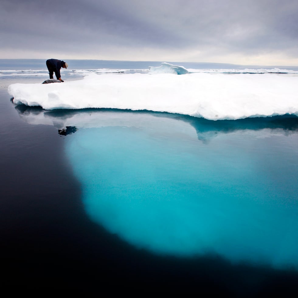 En esta foto de julio del 2007, un cazador de focas inuit toca una foca muerta sobre un iceberg derretido cerca de la isla de Ammassalik, en Groenlandia.