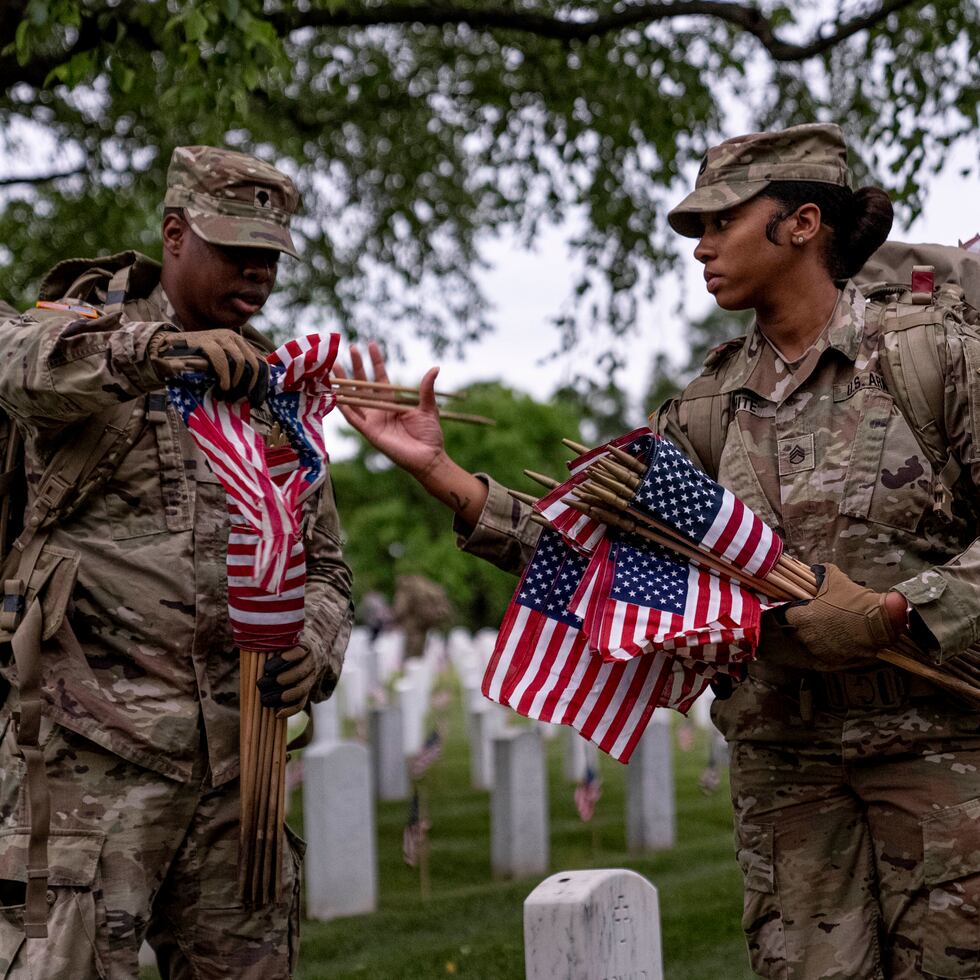 Miembros del 3er Regimiento de Infantería de EE.UU., también conocido como La Vieja Guardia, colocan banderas delante de cada lápida para el "Flags-In" al amanecer en el Cementerio Nacional de Arlington en Arlington, el jueves 25 de mayo de 2023, para honrar a los héroes militares caídos.