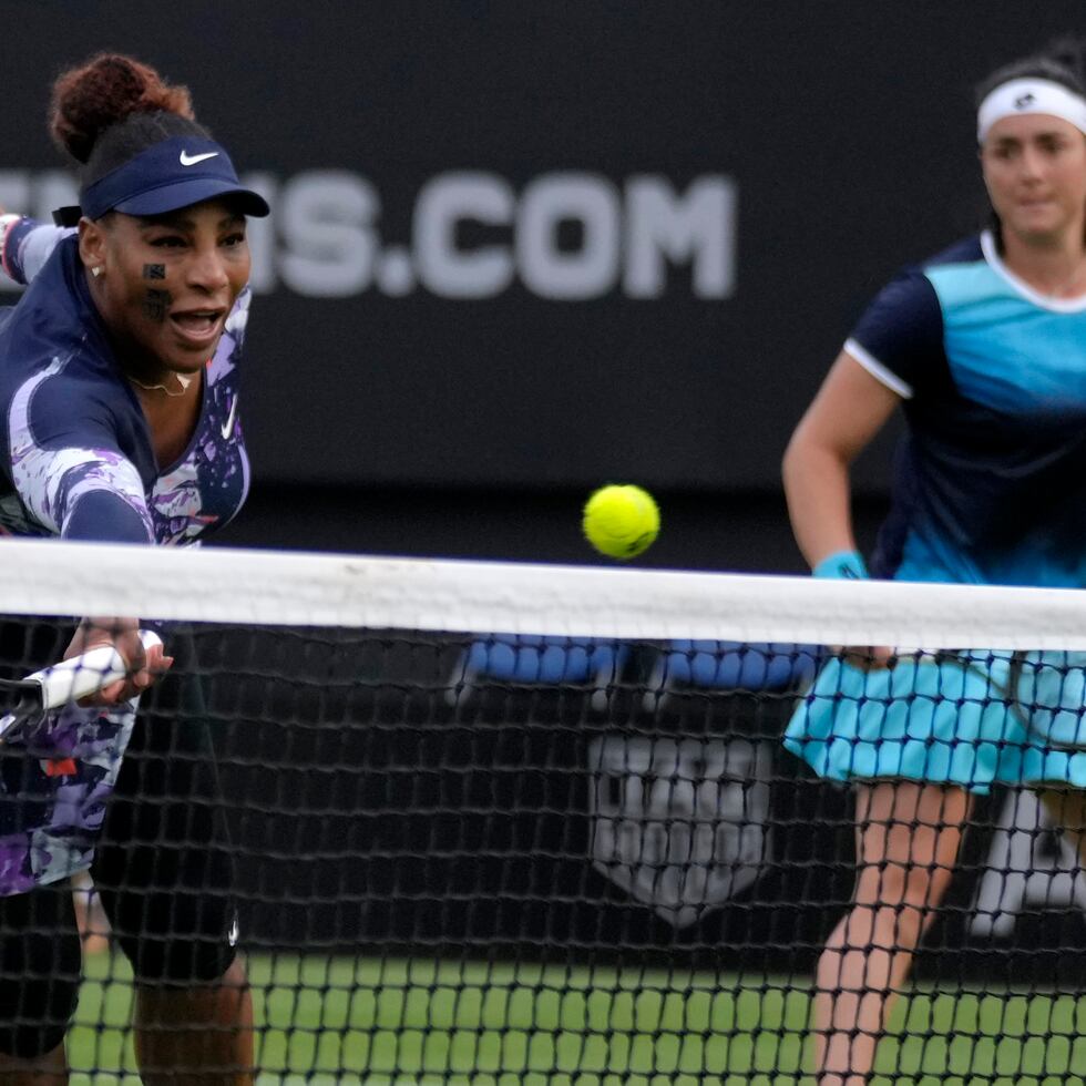 Serena Williams devuelve ante la mirada de Ons Jabeur durante un partido de dobles en el torneo de Eastbourne.