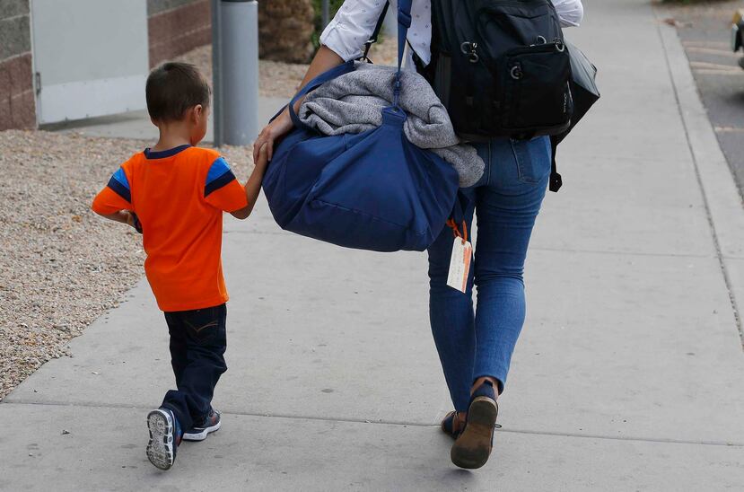 José Jr., de 3 años y natural de Honduras, recibe ayuda de una trabajadora del Southern Poverty Law Center antes de reunirse con su padre en Phoenix. (AP)